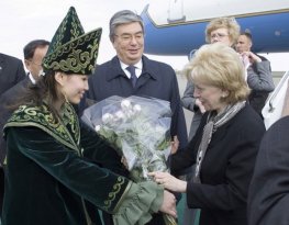 A Kazakh woman adorned in ceremonial dress presents a bouquet of flowers to Lynn Cheney, wife of Vice President Dick Cheney, as they both arrive in Astanta, Kazakhstan, Friday, May 5, 2006